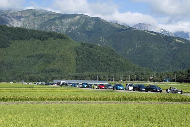 田の中を列で進むEV行進