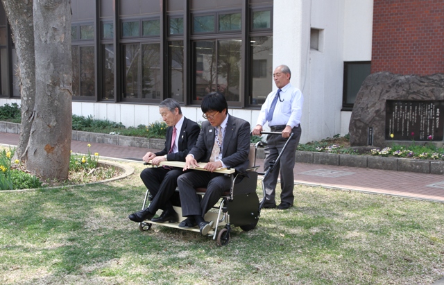 車いすの説明を受ける福祉課長を村長