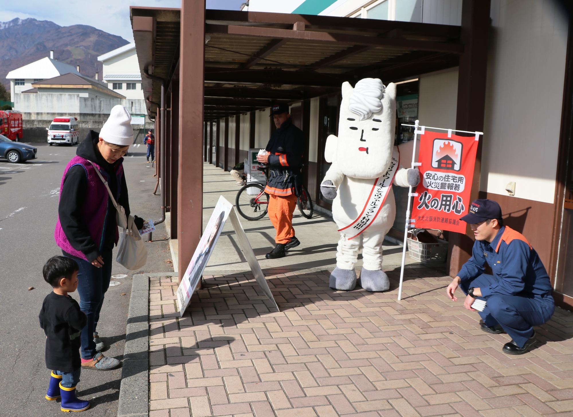 秋の火災予防運動 消防署職員とお店に来た母子とゆるキャラ村男三世