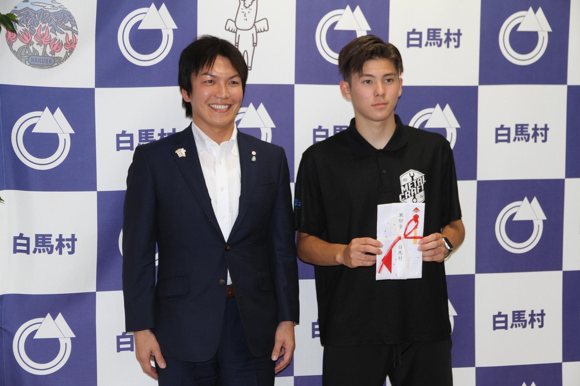 丸山村長と激励金を受け取った中尾グスタボさんが二人並んでいる写真