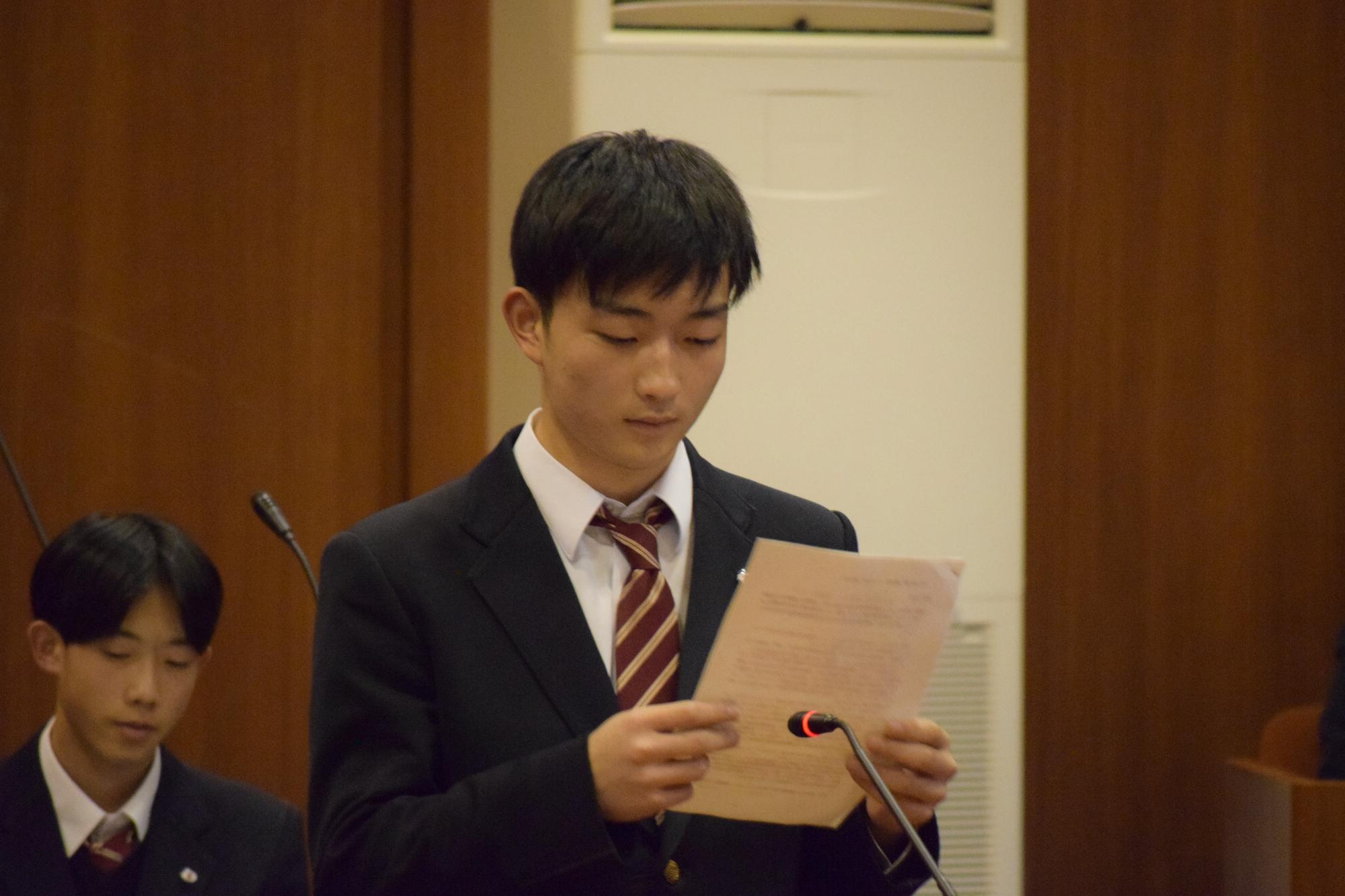 緊張した面持ちで村長に質問する中学生