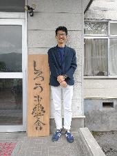 しろうま学舎の看板と満岡さん
