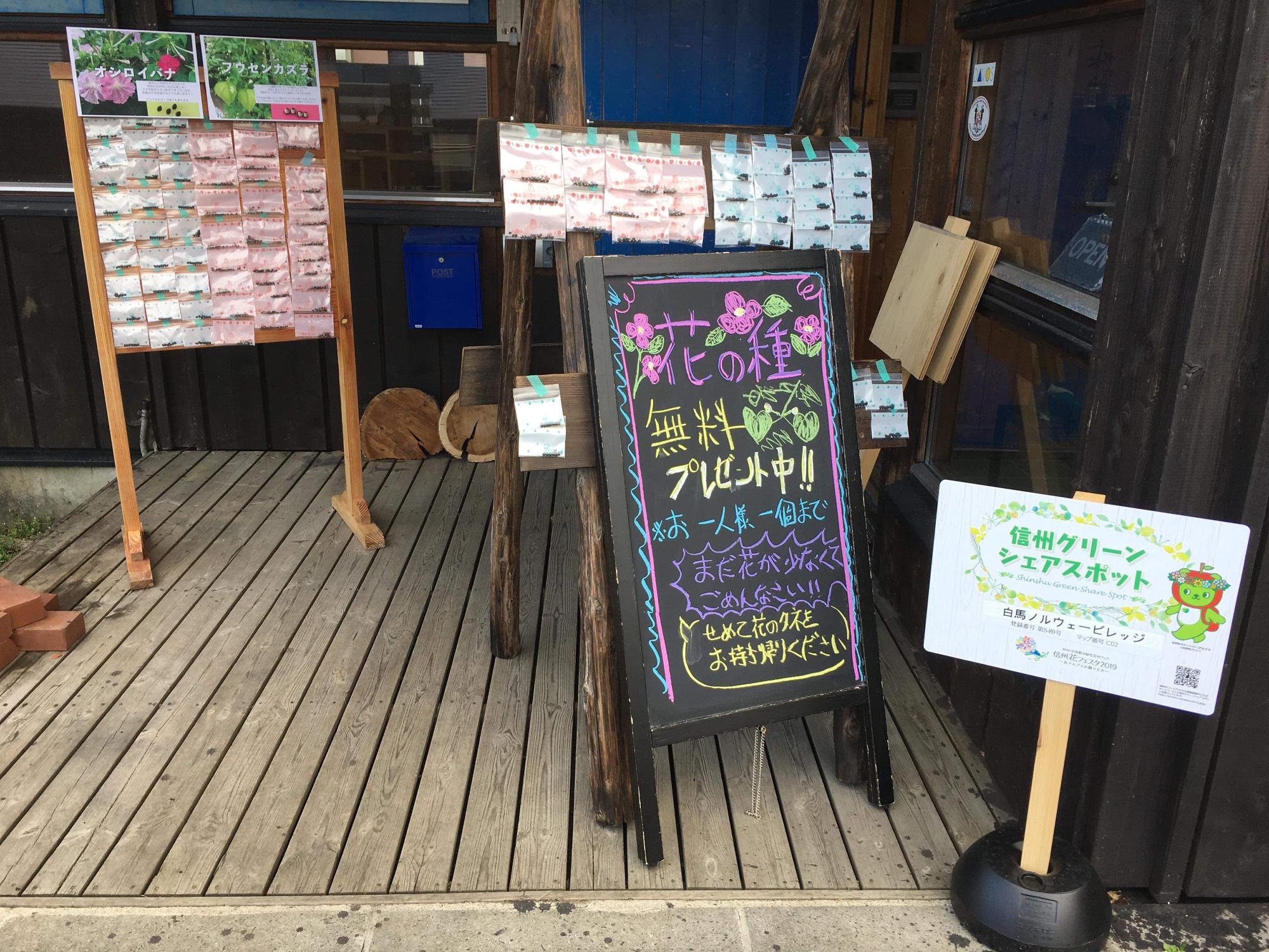 プレゼントを告知する看板や種の入った袋が貼り付けられているボードが並ぶノルウェービレッジの入り口の写真