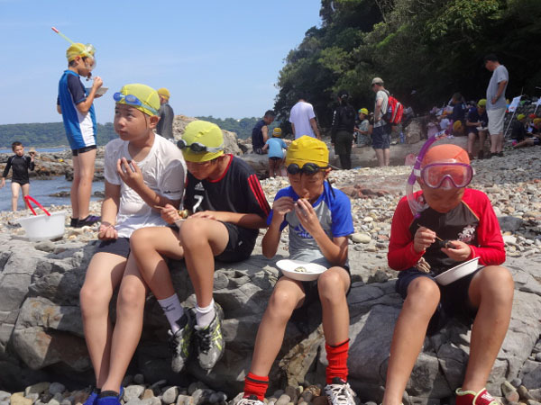 海辺で軽食の児童ら