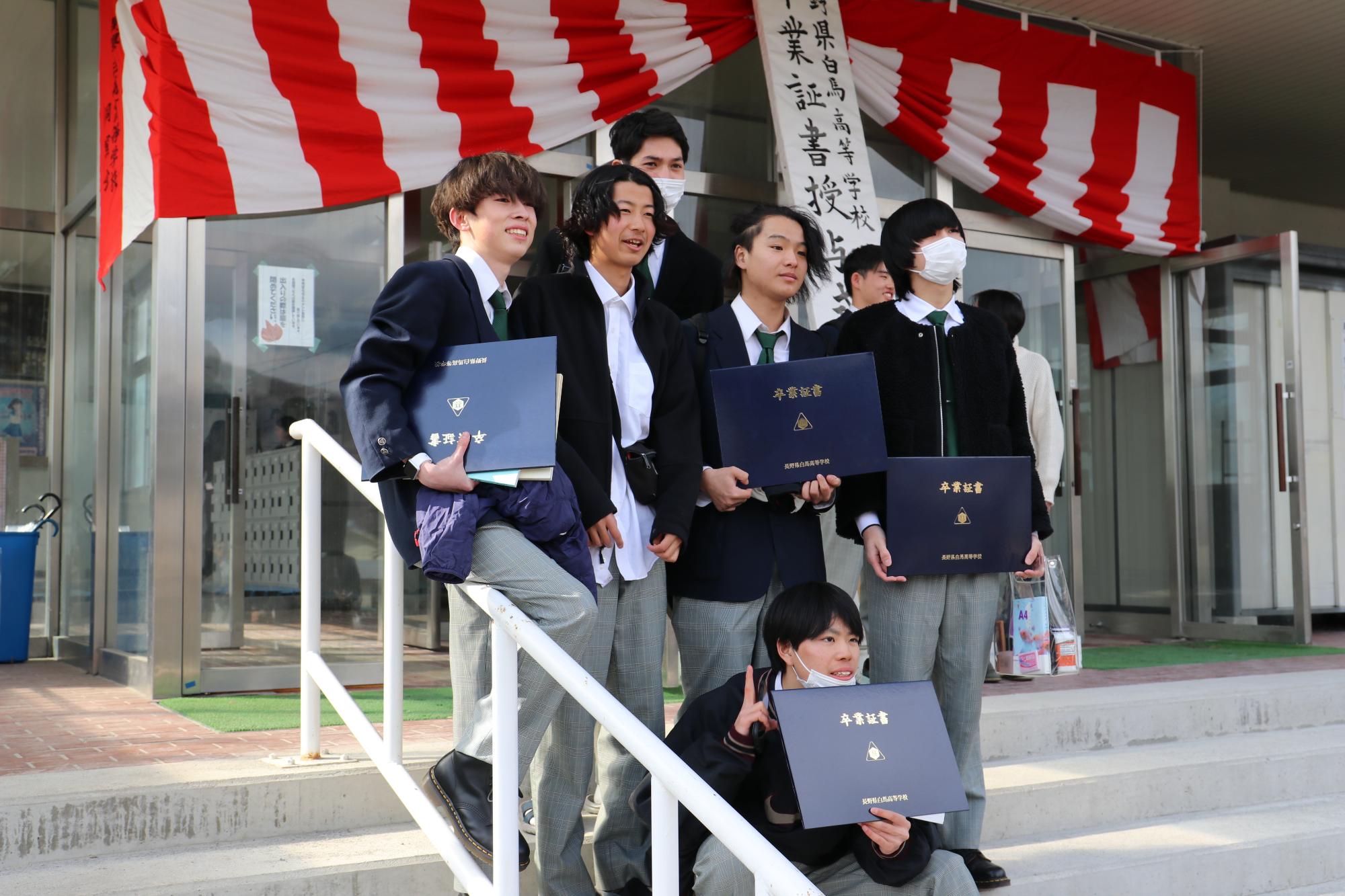卒業証書授与式終了後、昇降口前で写真撮影をする男子生徒たち