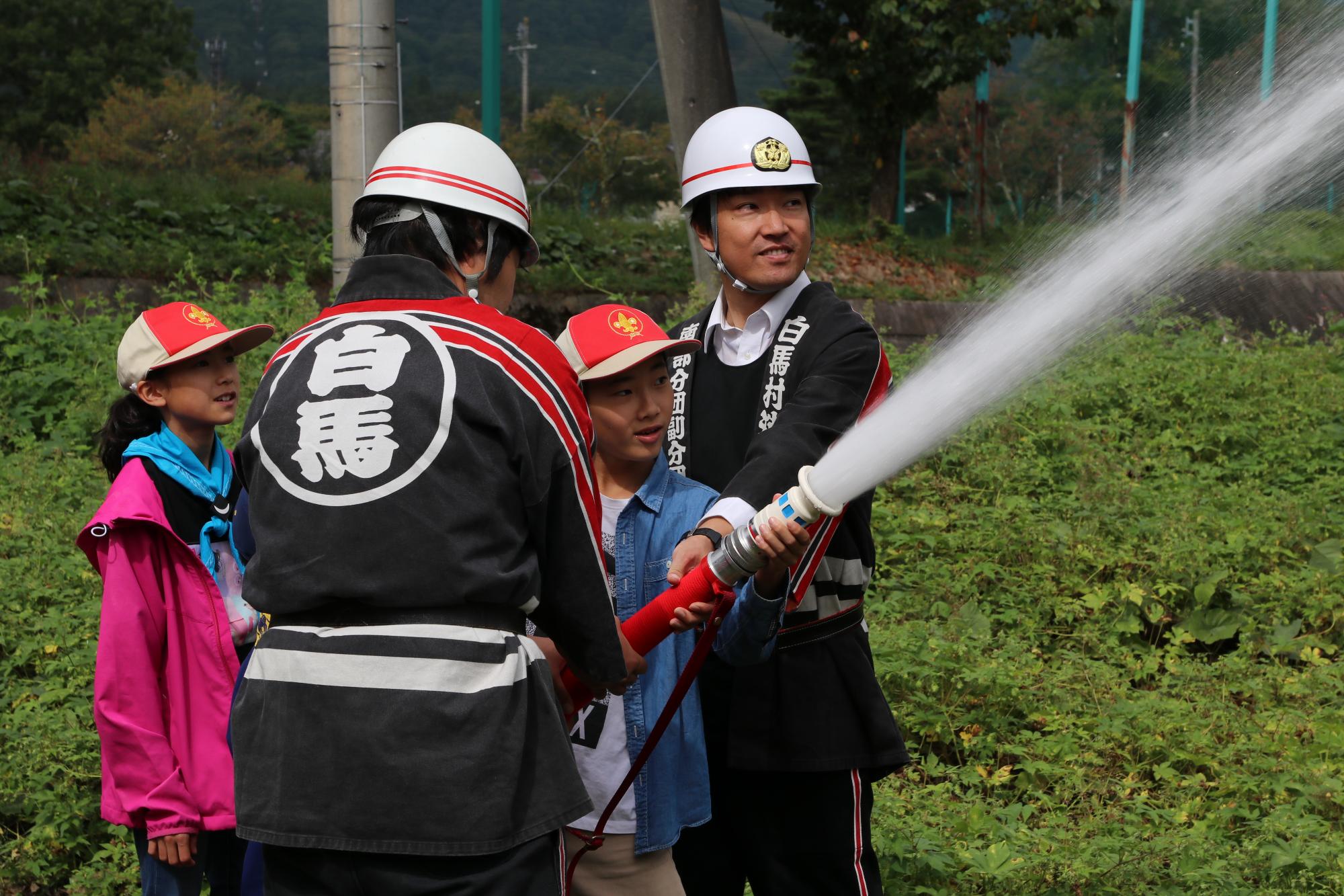 放水体験をする子どもとサポートする消防団員