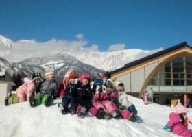 青空の下、たくさんの子どもたちが雪遊びをしている写真
