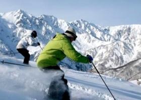 雄大な山々をバックに軽快にスキーをする2人の写真