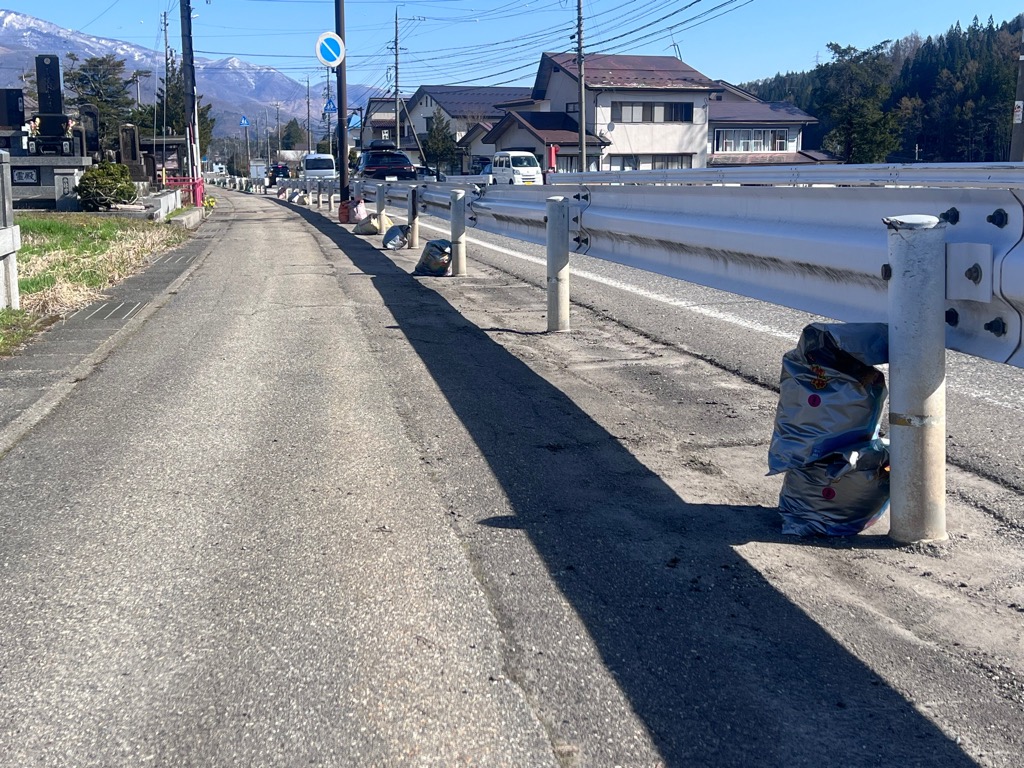 地区の皆様による道路清掃後、道端には土嚢袋が並びます
